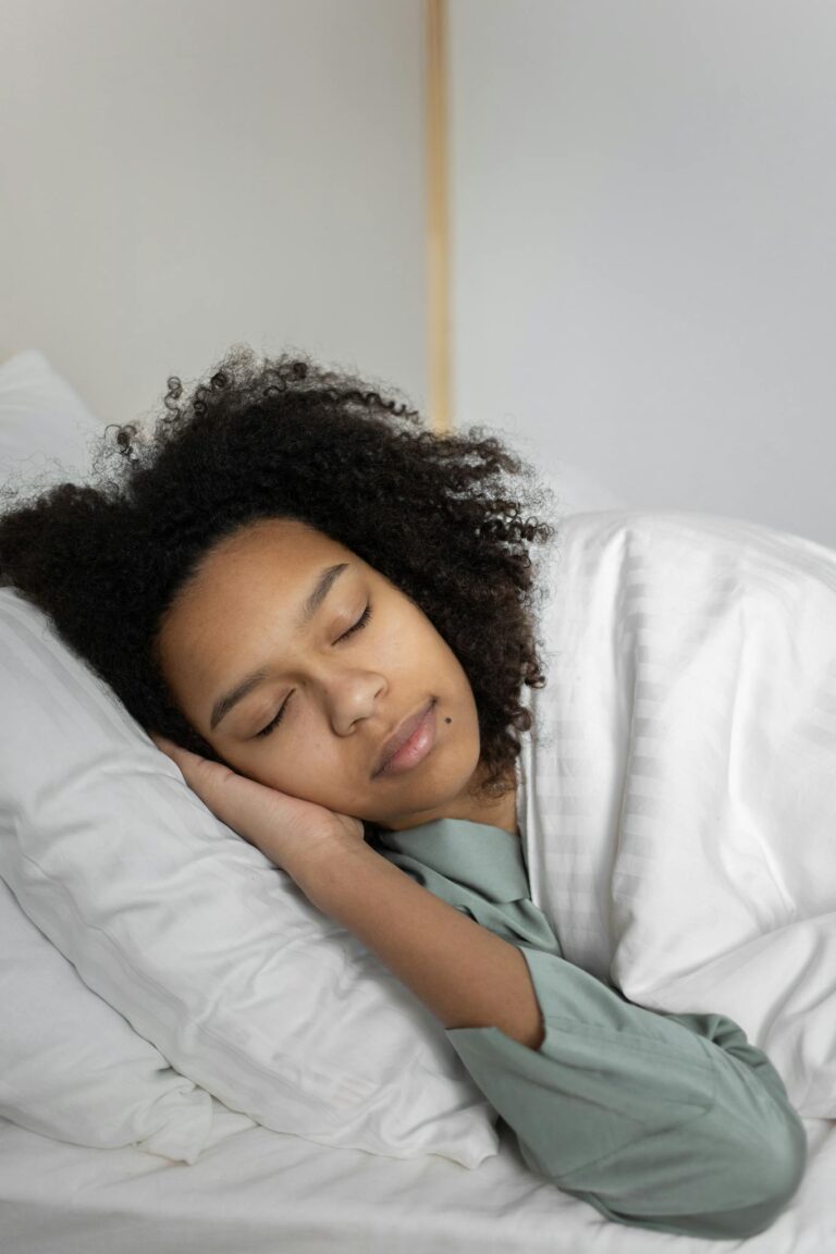 Relaxed woman with curly hair sleeping peacefully in a cozy bed.